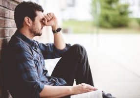 Lonely depressed person sitting near a brick wall